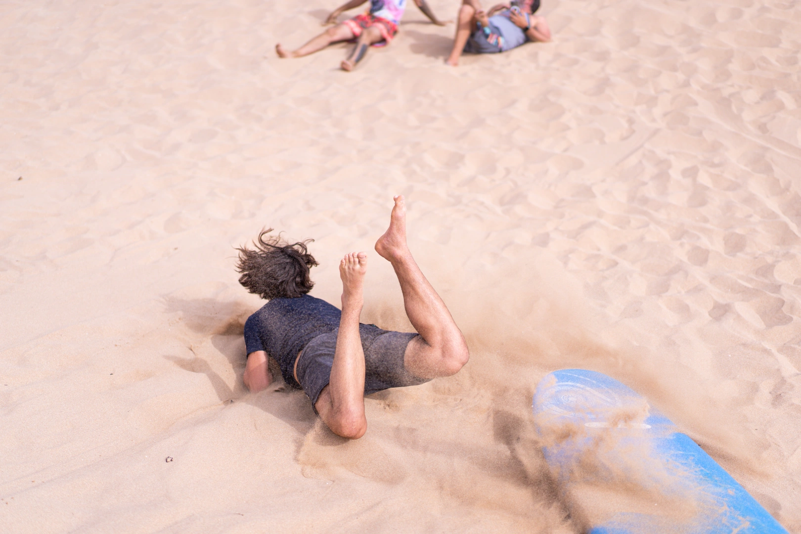 Personne s'amusant sur une planche de surf dans le sable au Maroc, illustrant l'expérience d'un surf camp et son coût.
