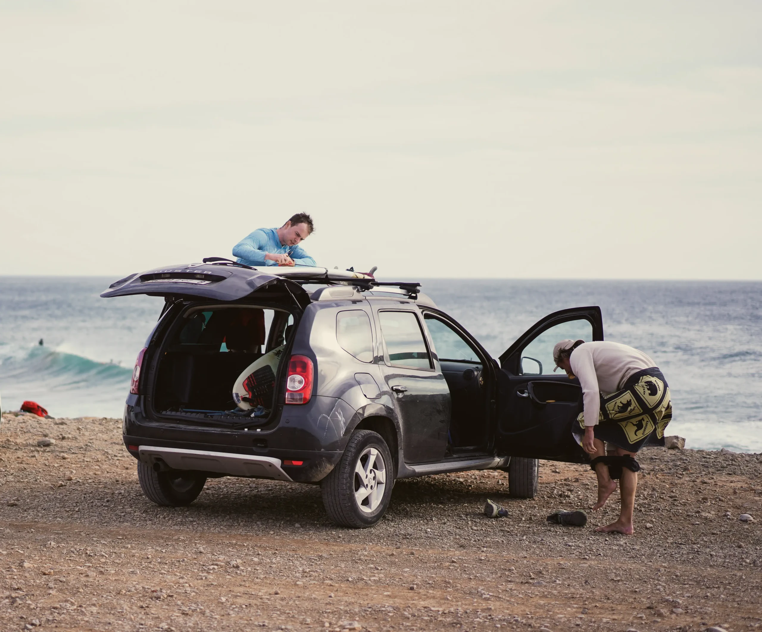 Surfeurs préparant leur équipement près de la plage pour une session de surf guidée.