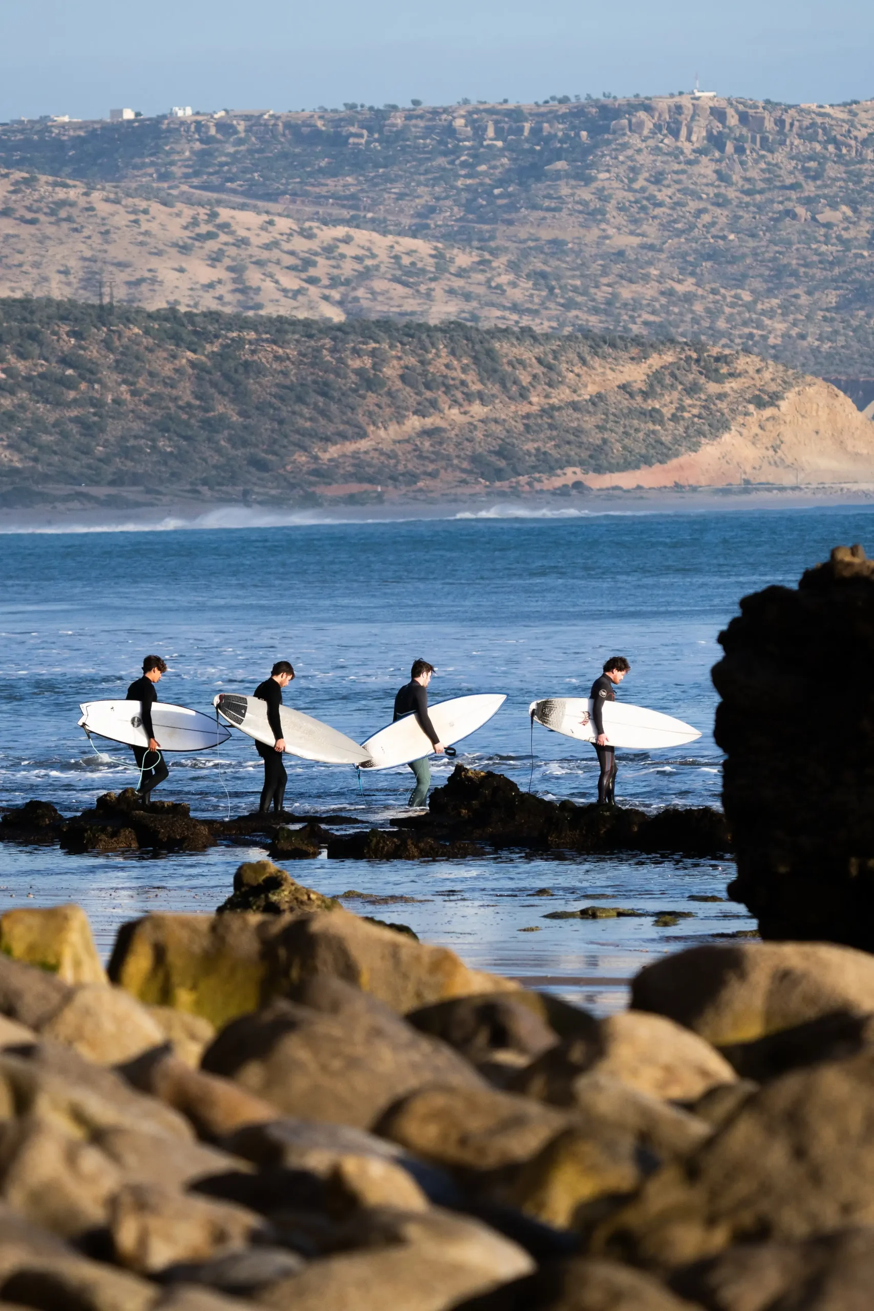 Surfeurs marchant sur les rochers à Imsouane, près du surf camp.