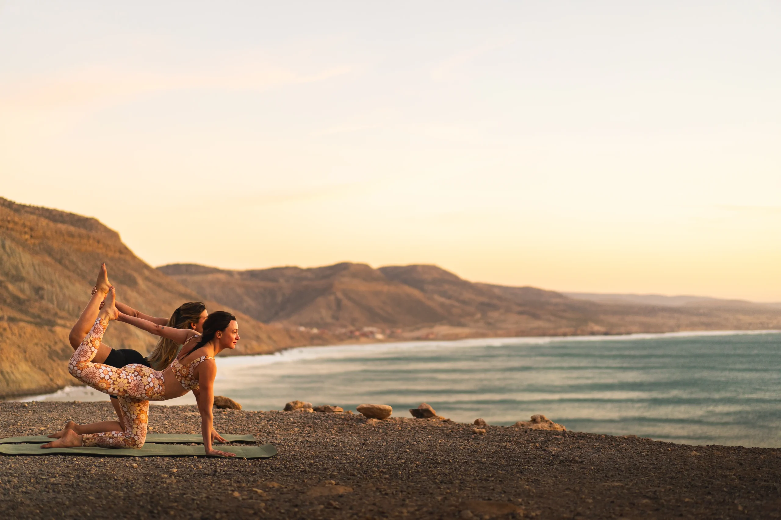 Deux personnes pratiquant le yoga au bord de la mer à Imsouane, Maroc.