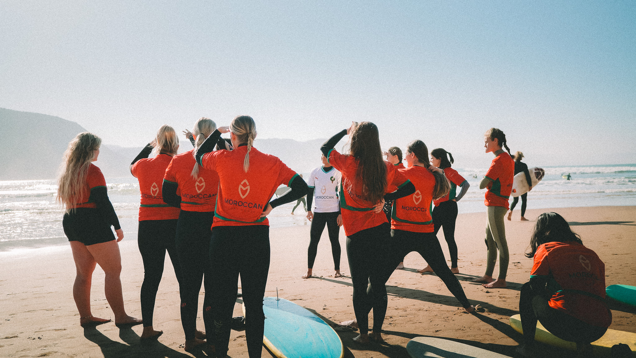 Groupe d'élèves en cours de surf à Imsouane avec un instructeur sur la plage, planches au sol. Découvrez le prix d'un...